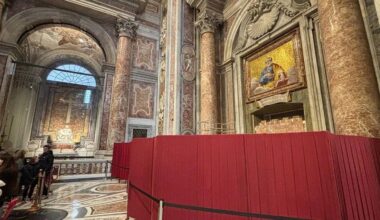 Wnętrze bazyliki z czerwonymi barierkami i fragmentem ołtarza.