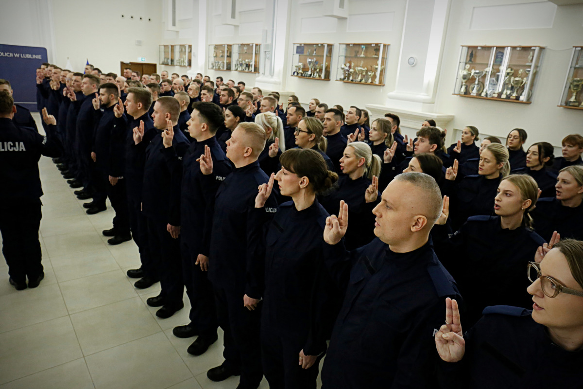 Nowi policjanci z uniesioną prawą dłonią wypowiadają słowa roty.