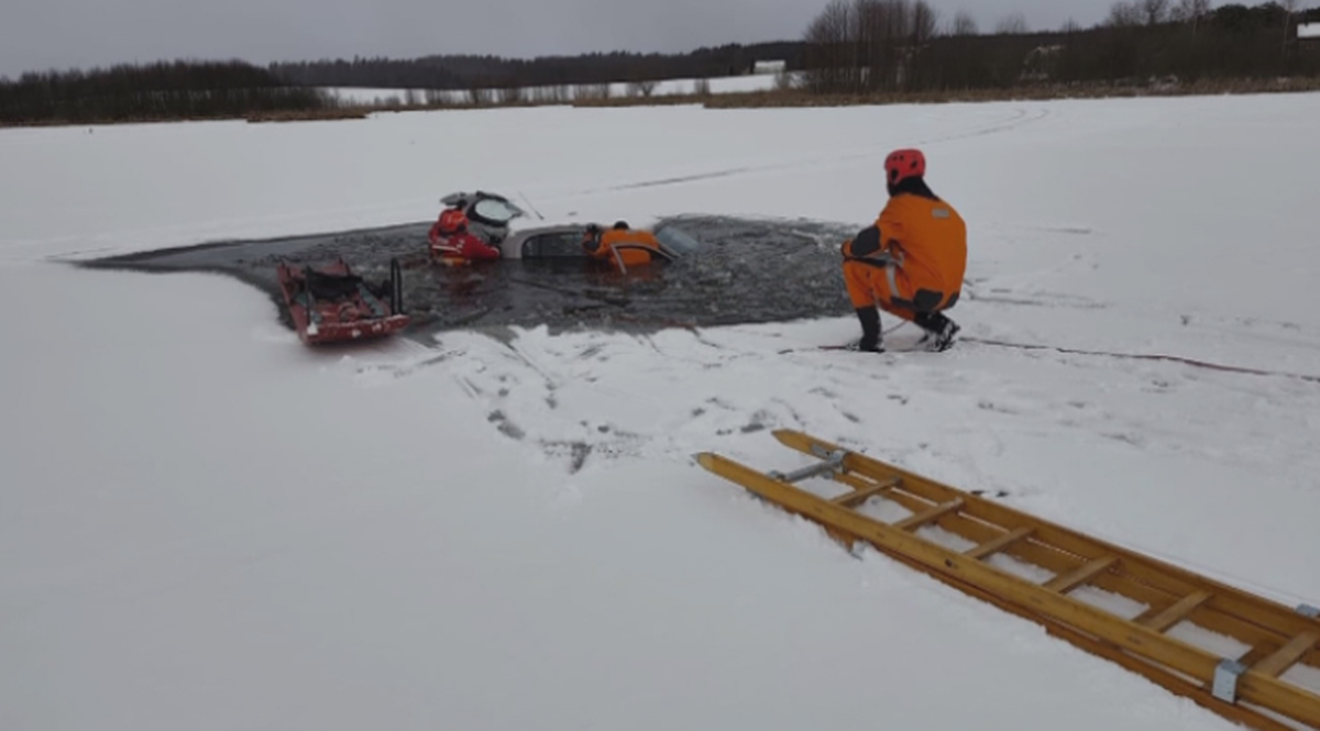 Akcja ratunkowa na lodzie, ratownicy wyciągają samoch&oacute;d spod wody.