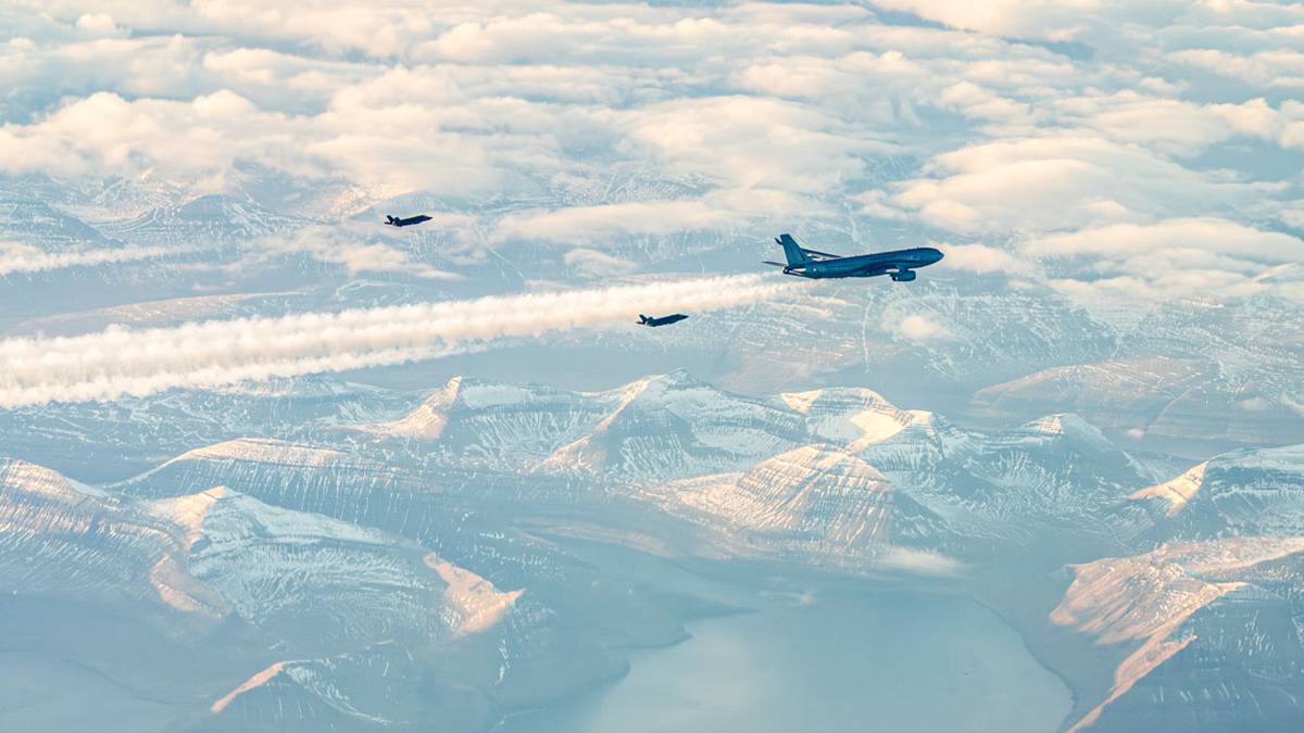 Trzy samoloty lecące nad arktycznymi g&oacute;rami i wodą, jeden większy niebieski i dwa mniejsze ciemne.