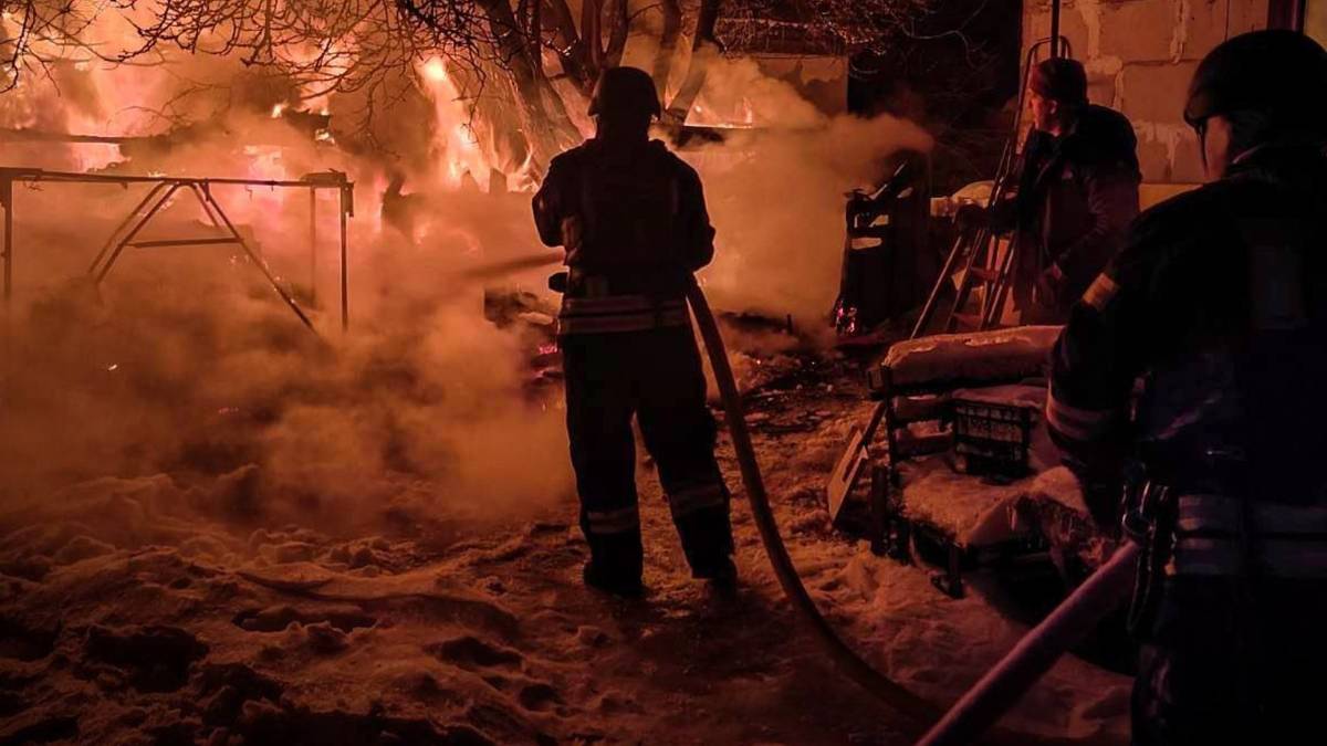Strażacy gaszą nocny pożar, widoczny dym i płomienie.