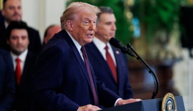 Donald Trump przemawia za m&oacute;wnicą, z gestem dłoni podkreślającym słowa.