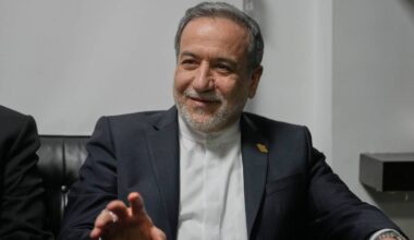 Mężczyzna w formalnym stroju siedzi i m&oacute;wi.