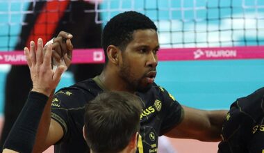 Grupa siatkarzy w ż&oacute;łtych i czarnych strojach cieszy się ze wsp&oacute;lnego zwycięstwa na boisku siatkarskim.