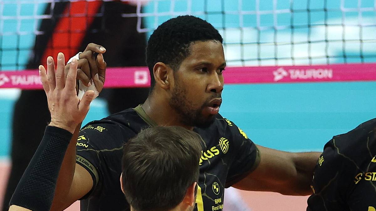 Grupa siatkarzy w ż&oacute;łtych i czarnych strojach cieszy się ze wsp&oacute;lnego zwycięstwa na boisku siatkarskim.