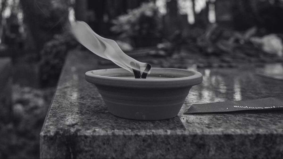 Płonący znicz na nagrobku.