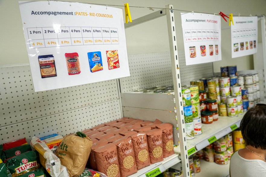 Plakat wskazuje liczbę punktów przysługujących beneficjentom w zależności od składu ich rodziny i gospodarstwa domowego, na paczki produktów skrobiowych i dodatków (ryż, makaron, kuskus), w ramach dystrybucji żywności w ośrodku Restos du Cœur w Valence