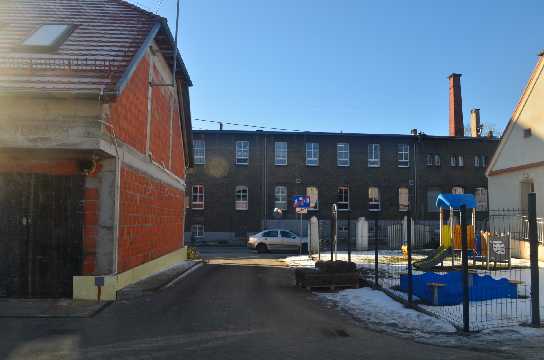 Wąska droga oddzielająca plac zabaw od budynku browaru 