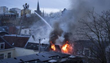 Strażacy gaszą pożar dachu budynku strumieniem wody z drabiny