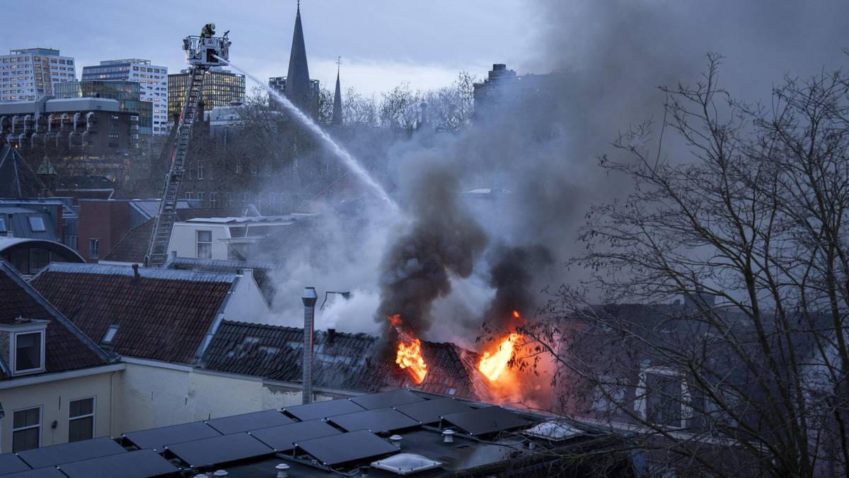 Strażacy gaszą pożar dachu budynku strumieniem wody z drabiny