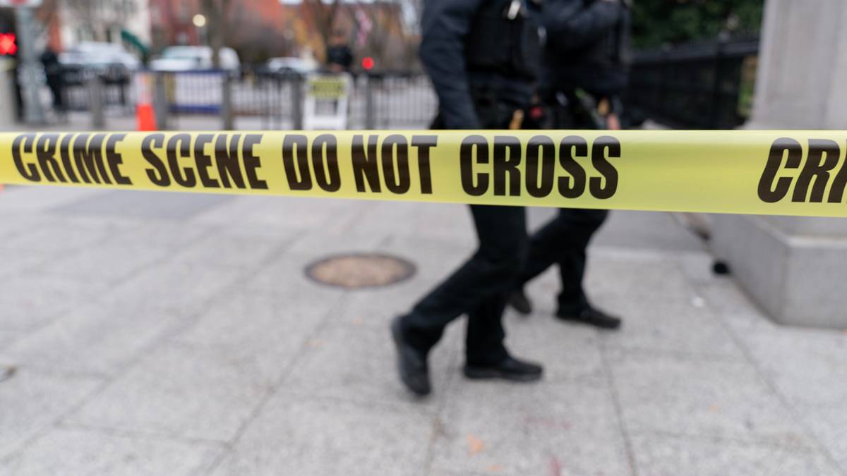 Dw&oacute;ch funkcjonariuszy policji przechodzi obok taśmy policyjnej "CRIME SCENE DO NOT CROSS"