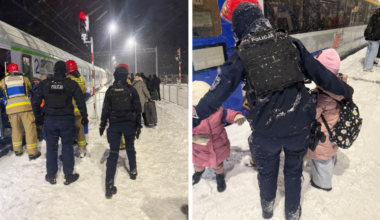 Służby ratownicze i policja pomagają pasażerom ewakuować się z pociągu stojącego na zaśnieżonym torowisku.