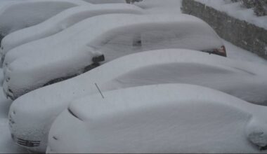 Rząd zaparkowanych samochod&oacute;w pokrytych grubą warstwą śniegu.
