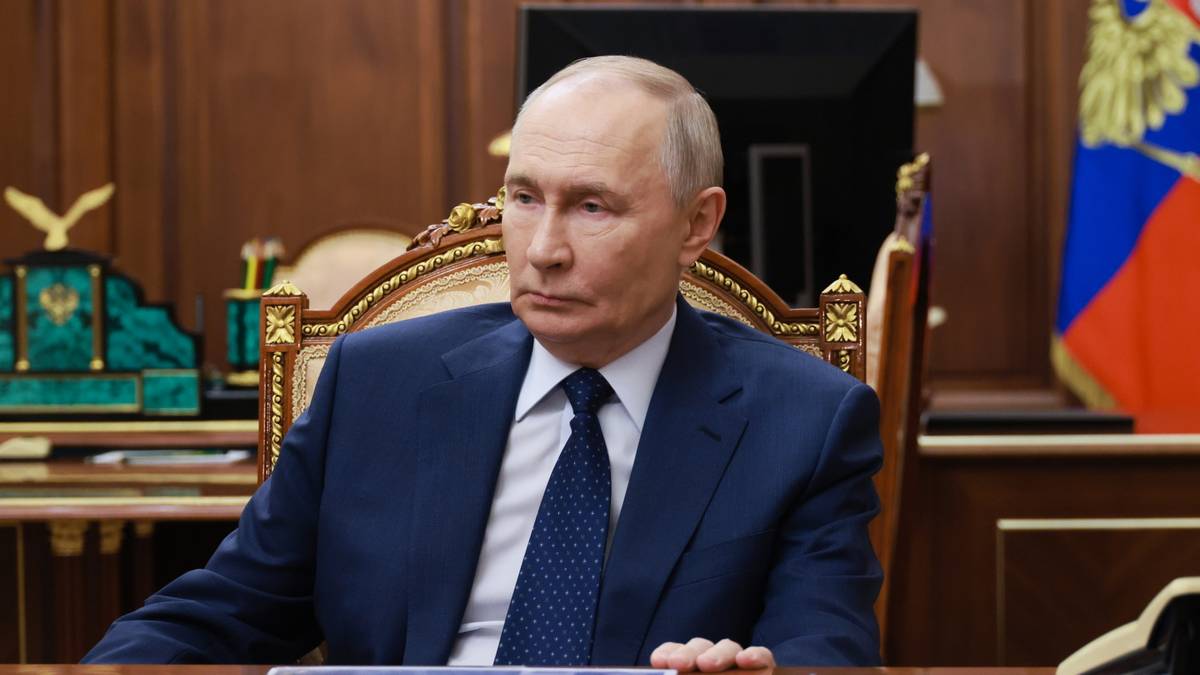 Władimir Putin siedzi przy biurku w gabinecie.