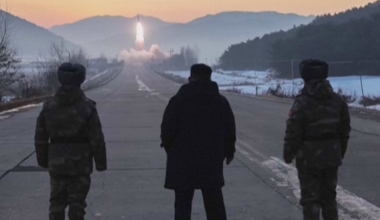 Trzech mężczyzn obserwuje start rakiety na tle zimowego krajobrazu.