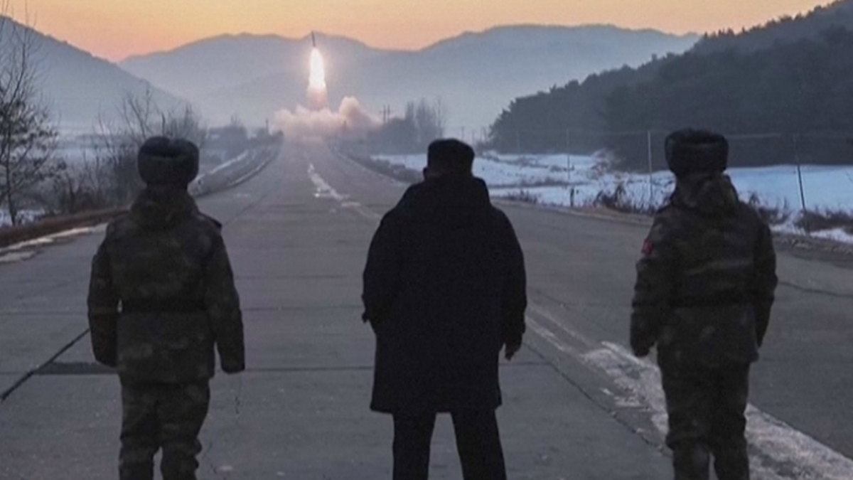 Trzech mężczyzn obserwuje start rakiety na tle zimowego krajobrazu.