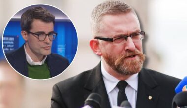 Portret dw&oacute;ch mężczyzn, jeden z nich m&oacute;wi do mikrofonu, drugi widoczny w okrągłym kadrze.