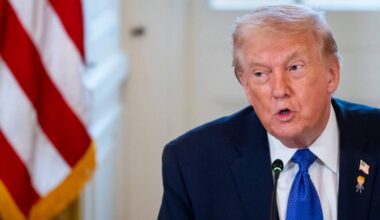 Donald Trump przemawia obok amerykańskiej flagi.