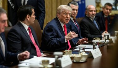 Grupa mężczyzn w garniturach siedzi przy długim stole w sali konferencyjnej, z prezydentem Donaldem Trumpem w centrum.