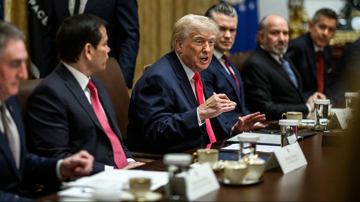 Grupa mężczyzn w garniturach siedzi przy długim stole w sali konferencyjnej, z prezydentem Donaldem Trumpem w centrum.