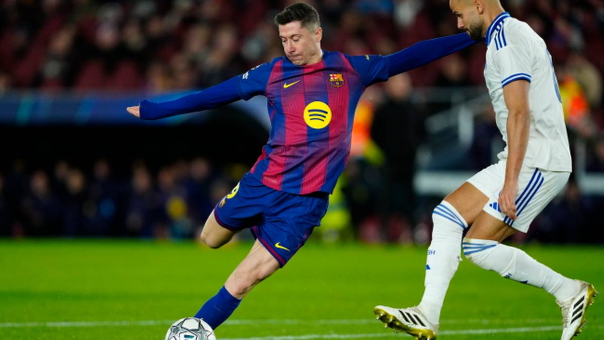 Piłkarz Robert Lewandowski w akcji na boisku, uderzający piłkę.