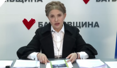 Julia Tymoszenko siedzi przy biurku, przed nią dokumenty.