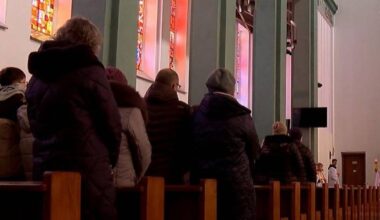 Grupa os&oacute;b siedzących w kościele, patrzących w stronę ołtarza.