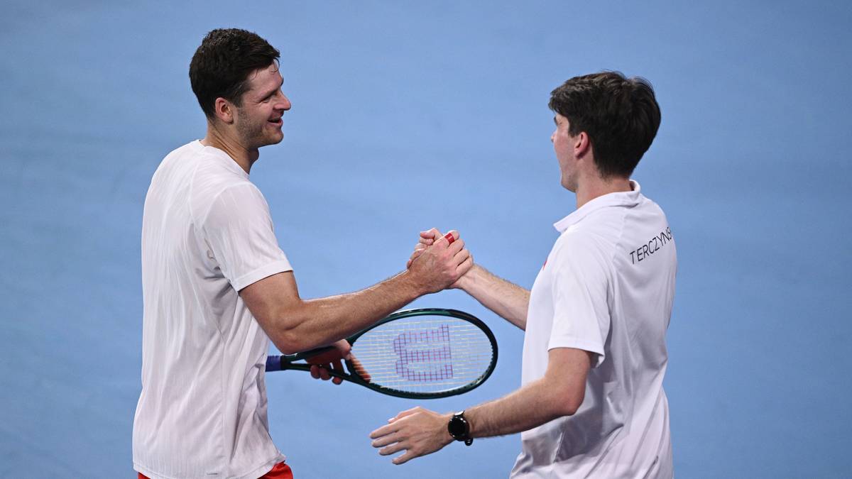 Dw&oacute;ch tenisist&oacute;w ściska sobie dłonie na korcie, jeden z nich trzyma rakietę.