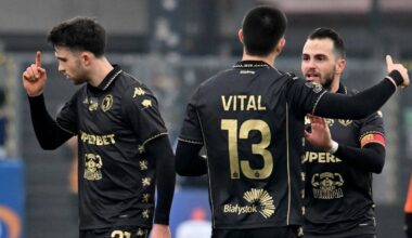 Trzech piłkarzy w czarnych strojach z numerami na plecach podczas meczu piłkarskiego.