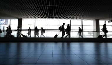 Sylwetki podr&oacute;żnych z walizkami na lotnisku lub dworcu.