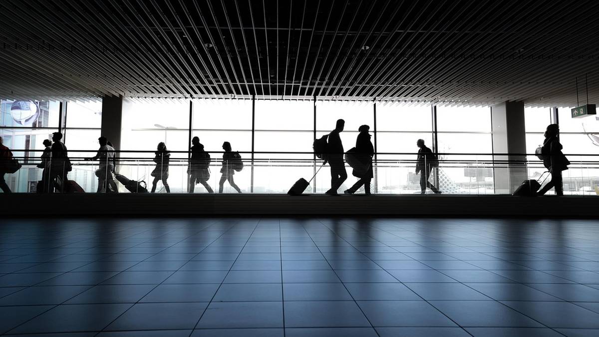 Sylwetki podr&oacute;żnych z walizkami na lotnisku lub dworcu.