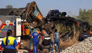 Zniszczony wagon kolejowy na miejscu wykolejenia w Tajlandii, wok&oacute;ł pracują ratownicy i służby porządkowe.