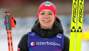 Narciarka biegowa z numerem startowym 49 na kamizelce, trzymająca kijki i narty.