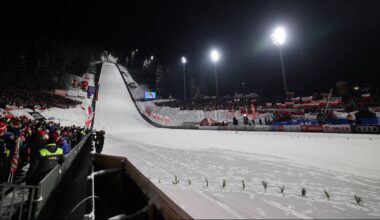 Skocznia narciarska nocą z oświetlonymi trybunami i widzami