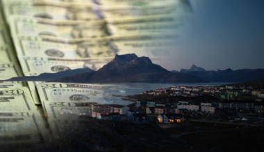 Banknoty dolarowe i panorama grenlandzkiego miasta.