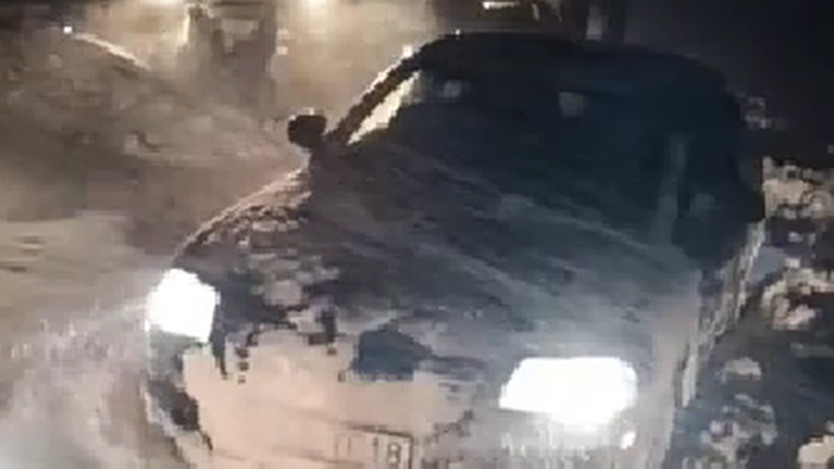 Samoch&oacute;d osobowy częściowo zasypany śniegiem, z przodu widoczny ciągnik pomocy drogowej w nocy.