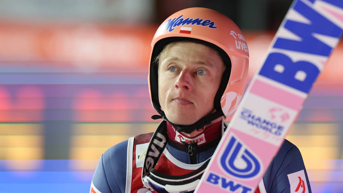 Skoczek narciarski w kasku, przygotowujący się do skoku.