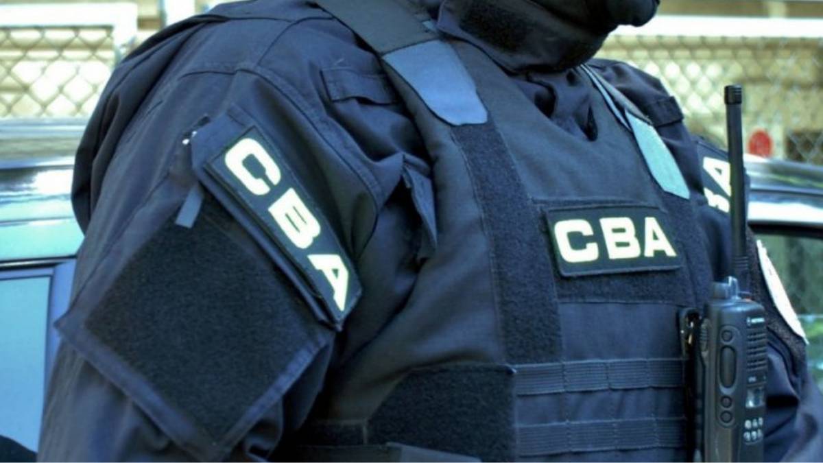 Funkcjonariusz CBA w mundurze z naszywkami CBA i radiotelefonem.