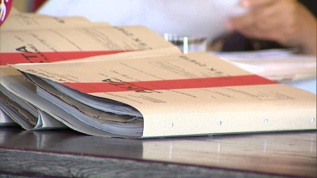 Stos papierowych dokument&oacute;w w teczkach, z czerwonym paskiem.