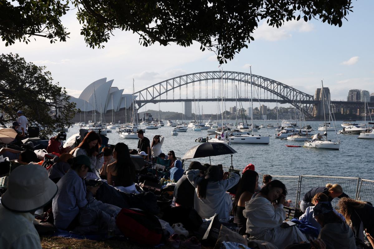 Ludzie siedzą na Mrs Macquaries Point z widokiem na Operę w Sydney i Most Sydney Harbour przed pokazem fajerwerków w sylwestra w Sydney, Australia, 31 grudnia 2025 r.