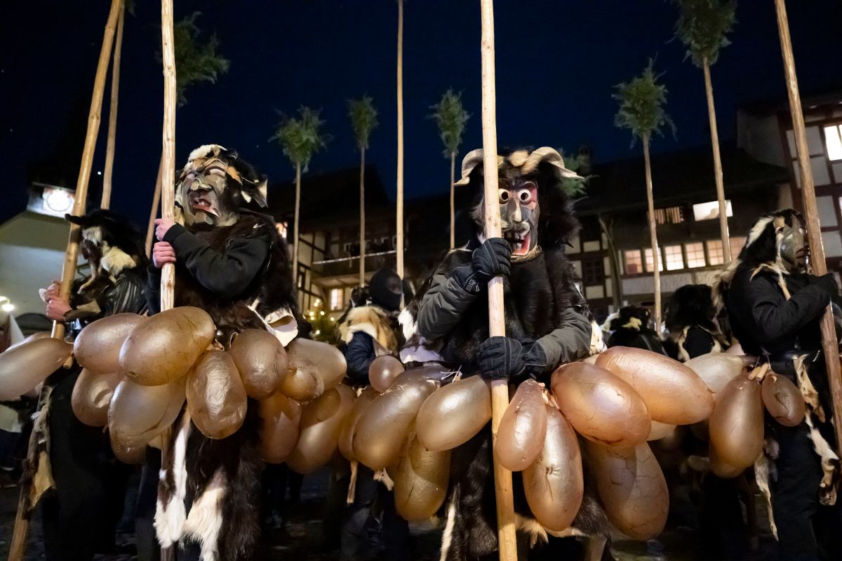 Młodzi 'Baesemanne' (ludzie z miotłami), wyposażeni w długie miotły jałowcowe, przerażające drewniane maski i wypełnione powietrzem świńskie pęcherze 'Soeiblaatere', paradują podczas 102. tradycyjnej procesji 'Achetringele' w sylwestra w Laupen w Szwajcarii, 31 grudnia 2025 r.