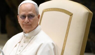 Portret papieża Leona XIV siedzącego na krześle, ubranego w białą sutannę.