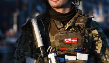 Duński żołnierz z flagami Grenlandii  (L) i Danii (P) na mundurze na posterunku kontrolnym w porcie Nuuk na Grenlandii, 26 stycznia 2026 r.