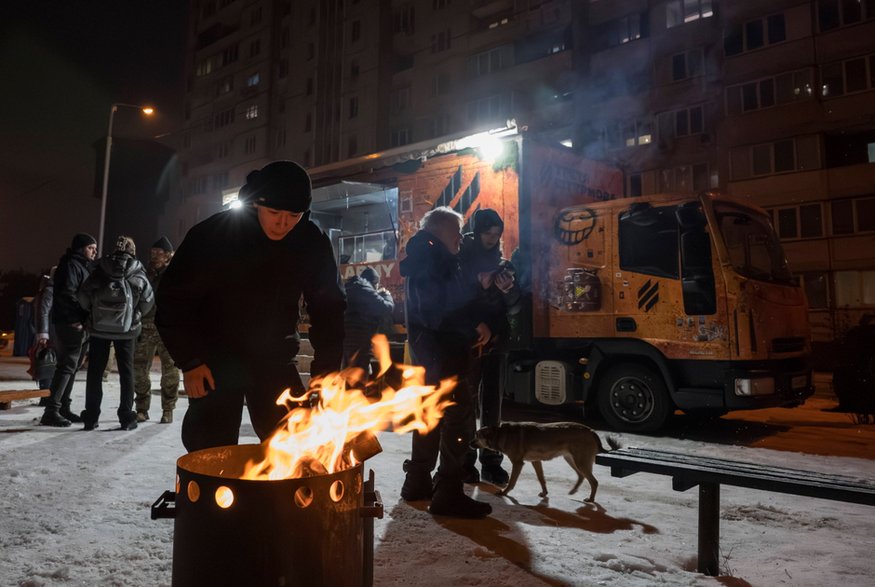  Mieszkańcy gromadzą się wokół ogniska w mobilnej kuchni w Kijowie w Ukrainie, 28 stycznia 2026 r.