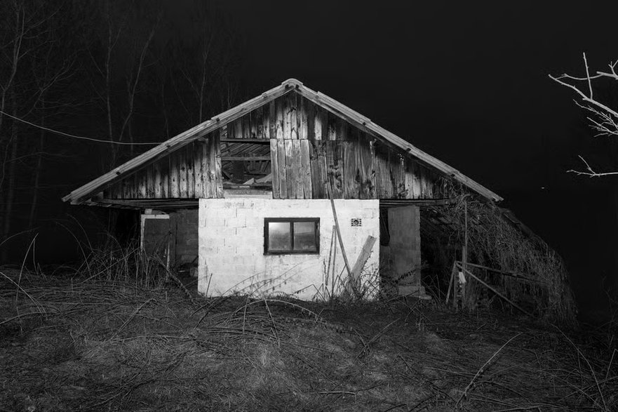 Czarno-białe zdjęcie przedstawia dom opuszczony w wyniku rozbudowy kopalni