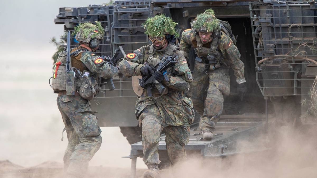 Trzech żołnierzy w umundurowaniu wychodzi z pojazdu wojskowego.