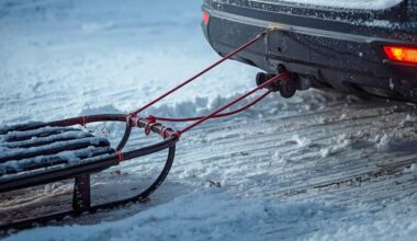 Sanki ciągnięte za tył samochodu po zaśnieżonej drodze.
