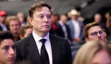 Elon Musk w garniturze i krawacie, patrzący w bok.