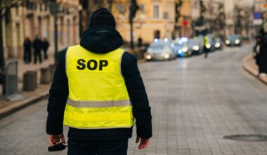 Funkcjonariusz SOP w kamizelce odblaskowej z napisem "SOP" na plecach stoi na ulicy.