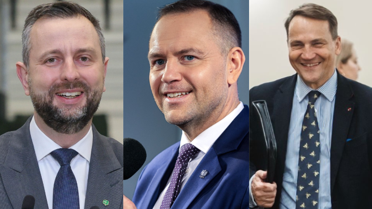 Trzech polityk&oacute;w w garniturach, z czego dw&oacute;ch uśmiechniętych.